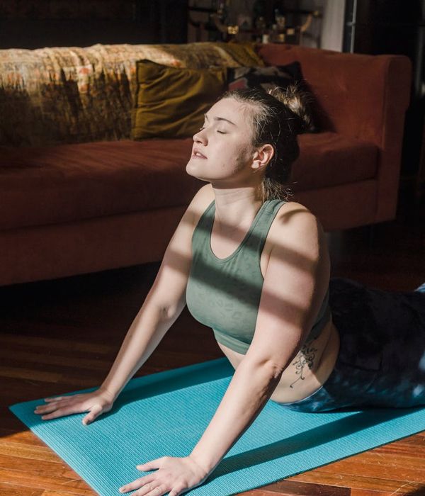 Senior woman smiling while performing a simple and gentle yoga stretch in a calm room.